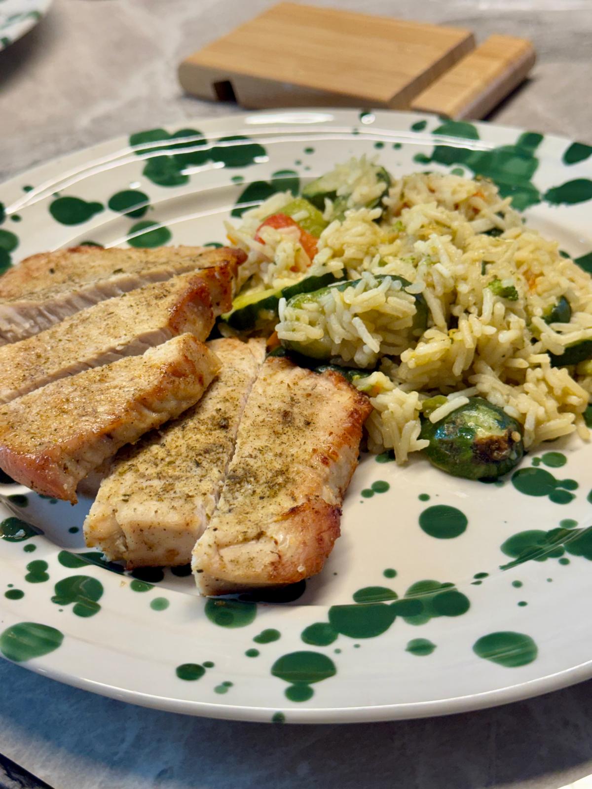 Sliced air-fryer turkey breast with basmati rice and Italian vegetables on a green-splatter plate