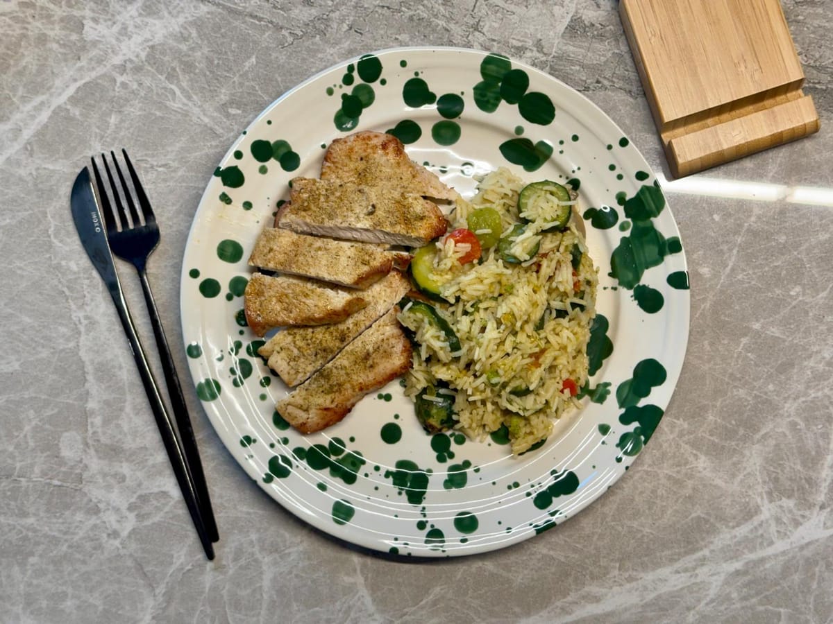 Air-fryer turkey breast sliced next to basmati rice and Italian vegetables on a green-splatter plate